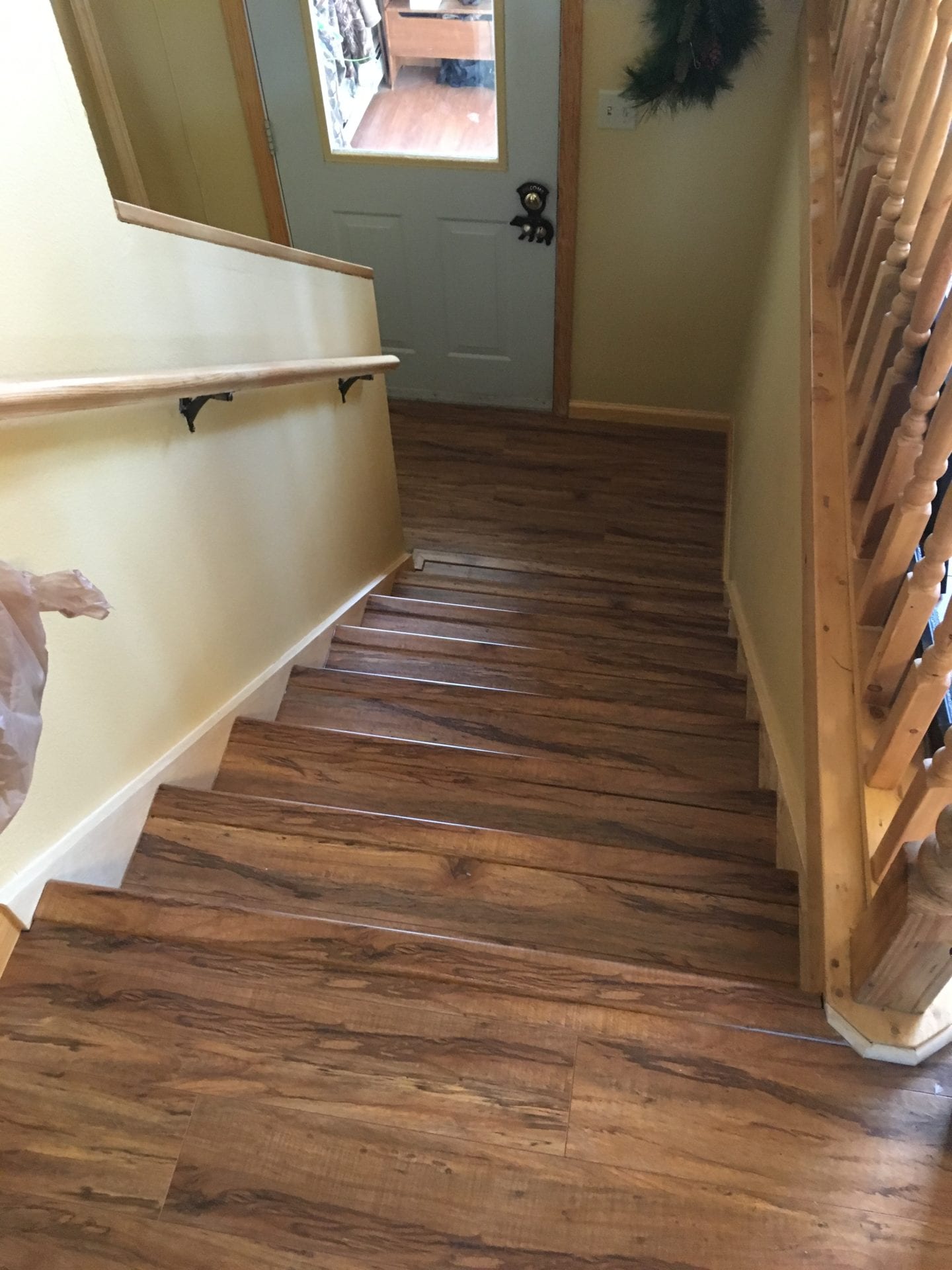 A wooden staircase with wood flooring and white walls.