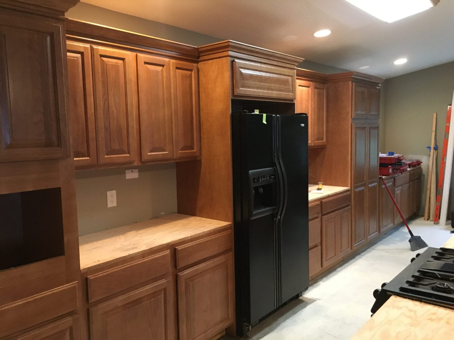 A kitchen with wooden cabinets and black refrigerator.